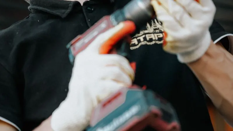 Technician installing overhead door hardware with a drill