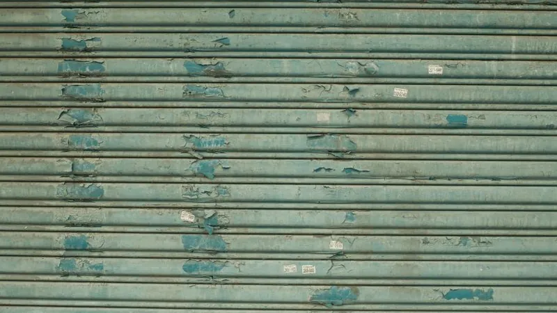 Weathered metal door with peeling paint from sun exposure